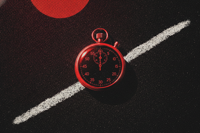 Red and black halftone illustration: a stopwatch lying on a chalk starting line on dark asphalt (TheNotificationApp)